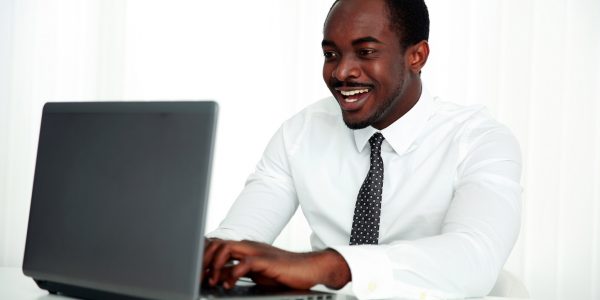 Laughing african man using laptop in office